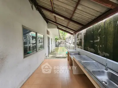 Spacious outdoor kitchen area with tiled flooring and stainless steel sink, perfect for outdoor cooking.