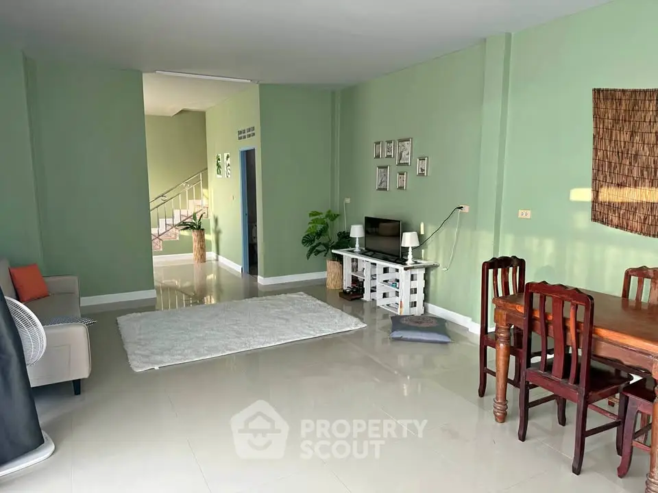 Spacious living room with green walls, cozy seating, and elegant dining area.