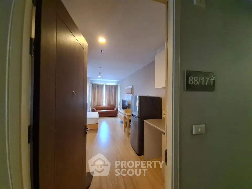 Modern apartment interior with open layout, featuring a cozy living area and kitchen appliances.