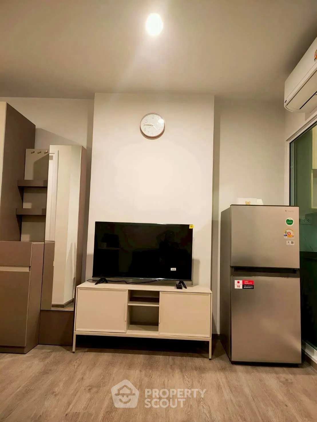 Modern living room with TV, fridge, and stylish decor in a cozy apartment.