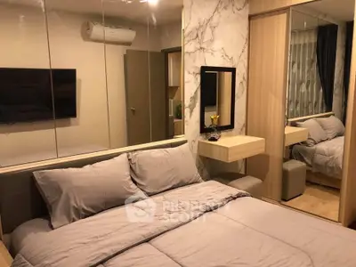 Modern bedroom with stylish decor and mirrored wall, featuring cozy bedding and a sleek air conditioning unit.