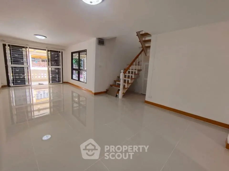 Spacious living room with glossy tiled floors and staircase in modern home