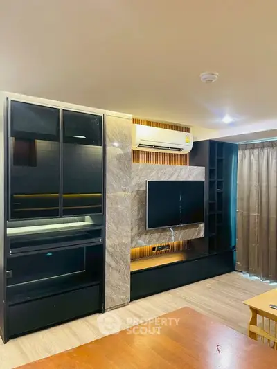 Modern living room with sleek entertainment center and air conditioning, featuring stylish lighting and wood flooring.