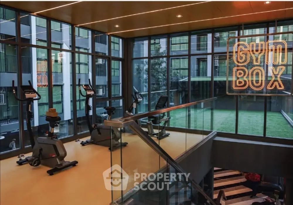 Modern gym with exercise bikes and glass walls overlooking green courtyard