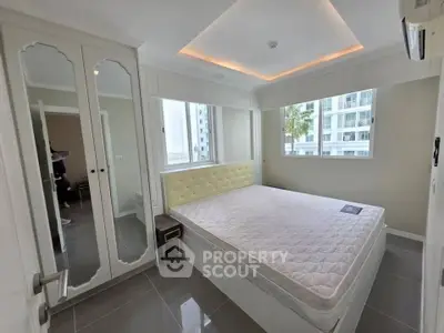 Modern bedroom with large windows and mirrored wardrobe in high-rise apartment.