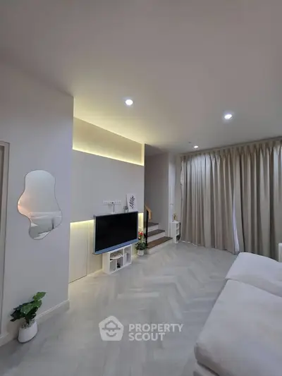 Modern living room with sleek design, featuring a wall-mounted TV, stylish lighting, and elegant curtains.