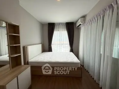 Spacious bedroom with modern furnishings and large windows for natural light.