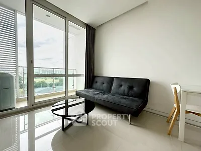 Modern living room with sleek black sofa and glass coffee table, featuring a spacious balcony with city view.