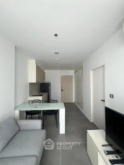 Modern living room with sleek kitchen and dining area in open layout apartment.