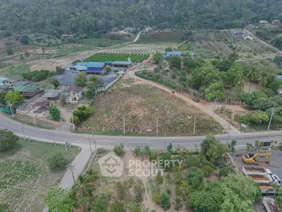 Aerial view of expansive land with lush greenery and road access, ideal for development opportunities.
