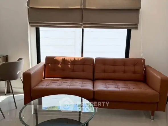Modern living room with stylish brown leather sofa and glass coffee table, perfect for contemporary homes.