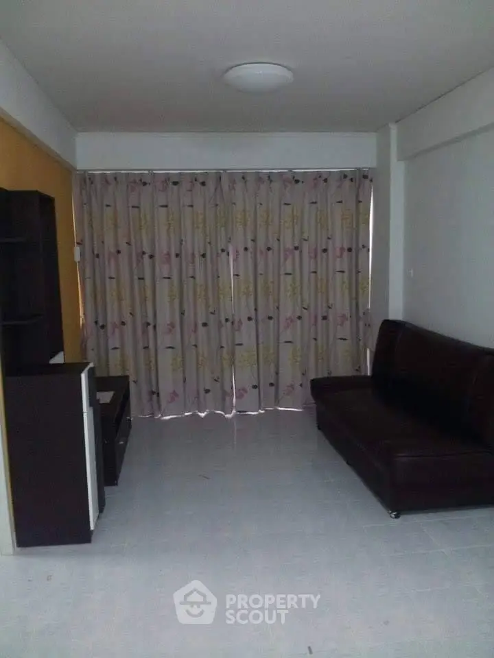 Cozy living room with dark sofa and floral curtains, ideal for relaxation.