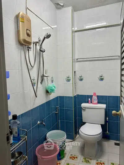 Compact bathroom with shower and toilet, featuring blue and white tiles and essential toiletries.