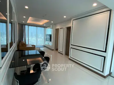 Modern living room with sleek design and city view, featuring a glass dining table and cozy seating area.