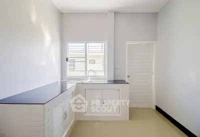 Modern minimalist kitchen with sleek countertops and ample natural light.