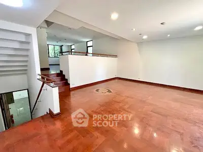 Spacious open-plan living room with wooden flooring and modern design.