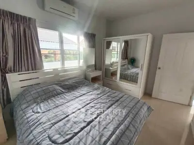 Cozy bedroom with modern furnishings and ample natural light, featuring a large mirrored wardrobe and air conditioning.