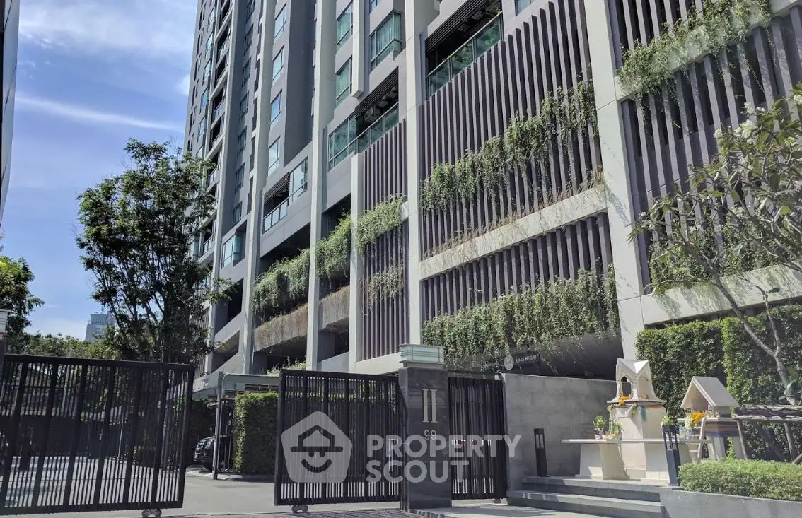 Modern high-rise building with lush greenery and secure gated entrance