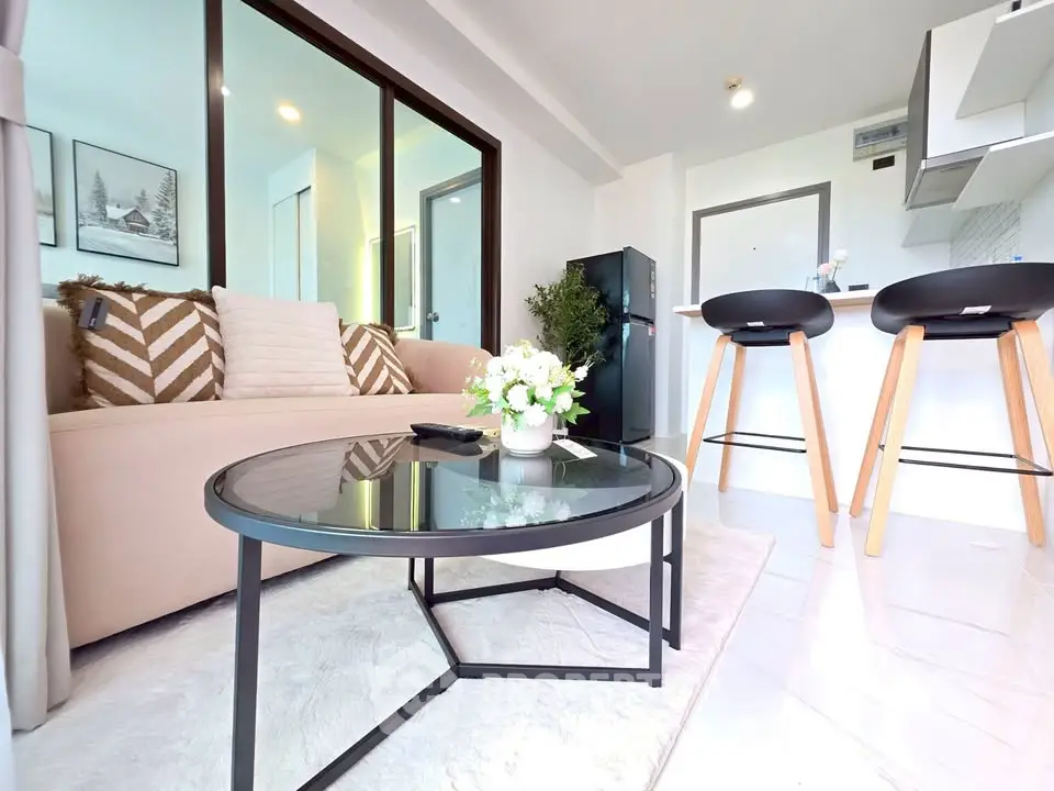 Modern living room with stylish decor and open kitchen layout, featuring cozy seating and elegant furnishings.