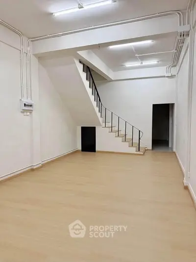 Spacious interior with modern staircase and wooden flooring, ideal for versatile use.