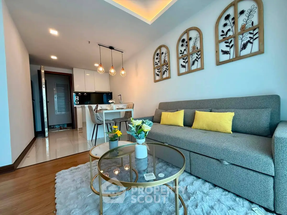 Modern living room with stylish decor and open kitchen layout, featuring elegant lighting and cozy seating area.