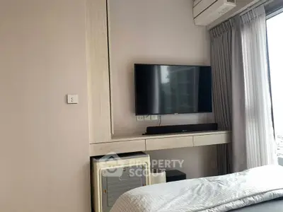 Modern bedroom with wall-mounted TV and air conditioning, featuring sleek design and natural light.