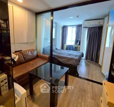 Modern studio apartment with glass partition, cozy living area, and stylish bedroom.