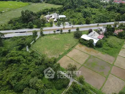 Aerial view of expansive green land with road access and surrounding nature.