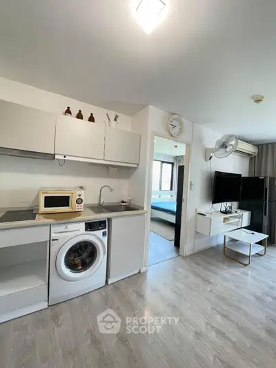 Modern open-layout kitchen with washing machine and sleek decor in a bright apartment.