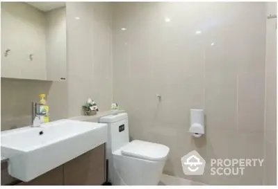 Modern bathroom with sleek white fixtures, wall-mounted toilet, and neutral tiled walls offering a clean and minimalist aesthetic.