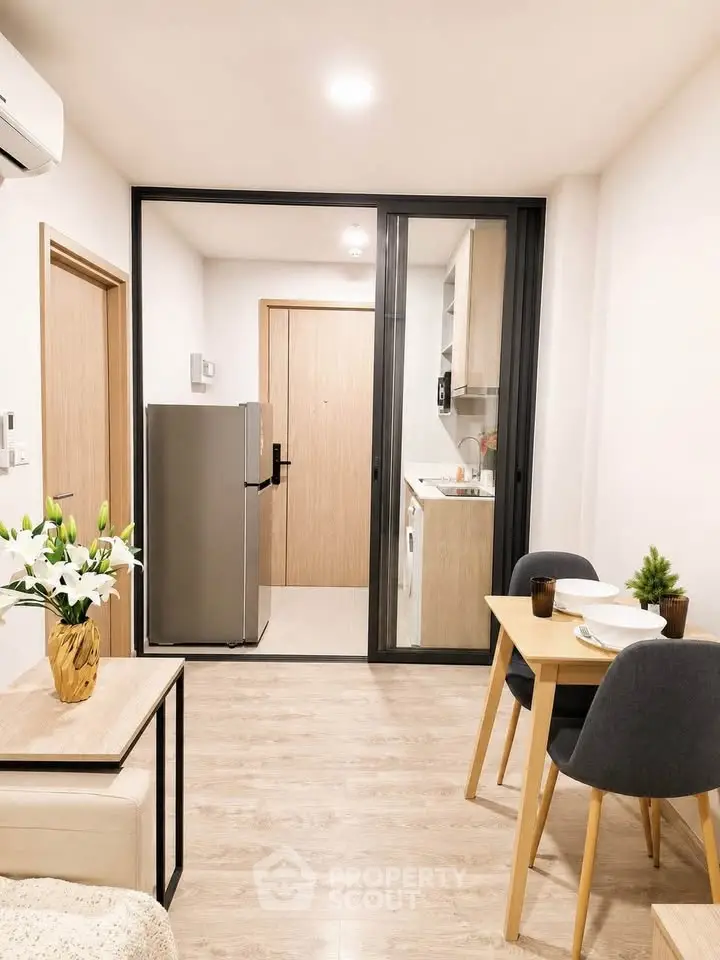 Modern open-plan living area with dining set and kitchen appliances in a cozy apartment.