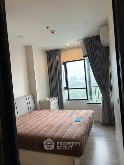 Cozy bedroom with large window offering city views, featuring modern furnishings and neutral decor.