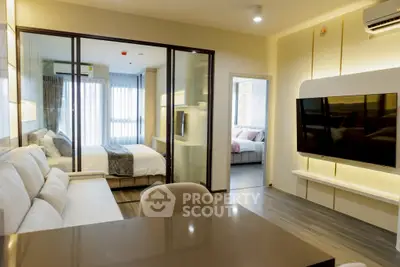 Modern apartment interior with open living room and bedroom, featuring sleek design and large TV.