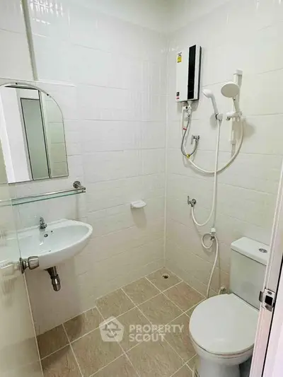 Modern bathroom with white tiles, shower, and sleek fixtures.