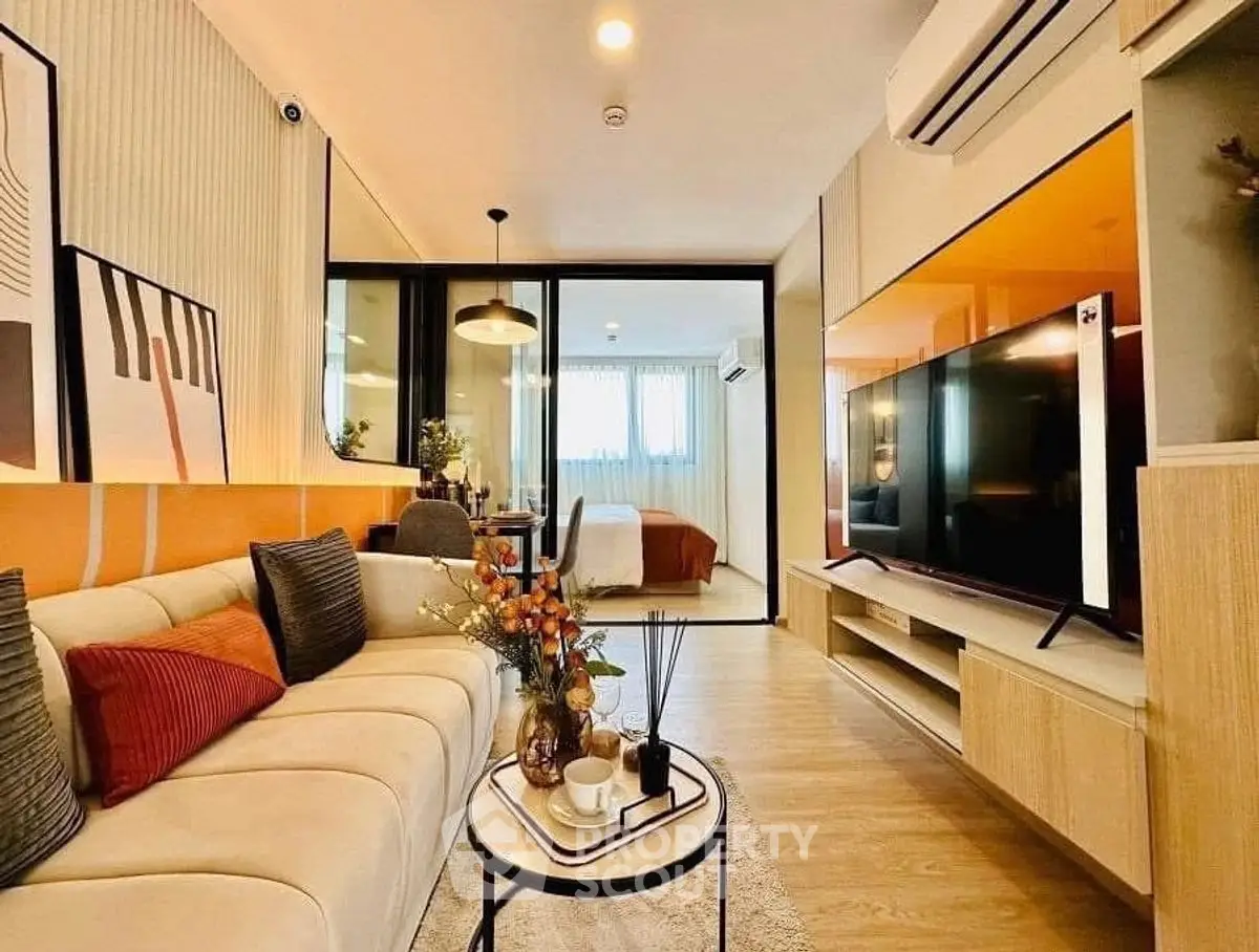 Modern living room with stylish decor and open layout, featuring a cozy sofa and large TV.