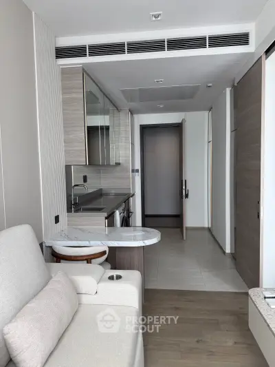Modern apartment interior with sleek kitchen and cozy living area, featuring contemporary design and high-end finishes.