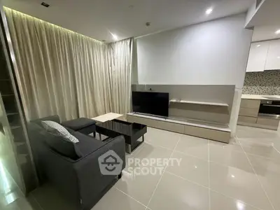 Modern living room with sleek furniture and open kitchen layout in a stylish apartment.