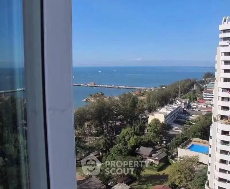 Stunning ocean view from high-rise apartment window, showcasing lush greenery and vibrant cityscape.