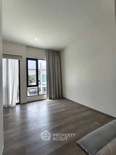 Spacious empty room with large windows and wooden flooring, perfect for customization.