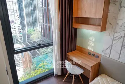 Modern bedroom with city view, featuring a sleek wooden desk and large window.