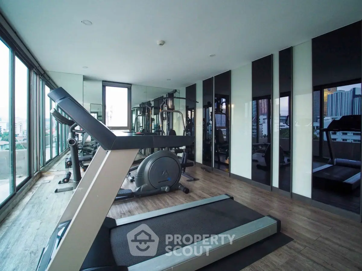 Modern gym with city view and state-of-the-art equipment in luxury building.