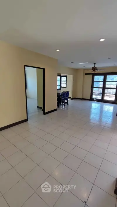 Spacious living room with large windows and tiled flooring in a modern home.