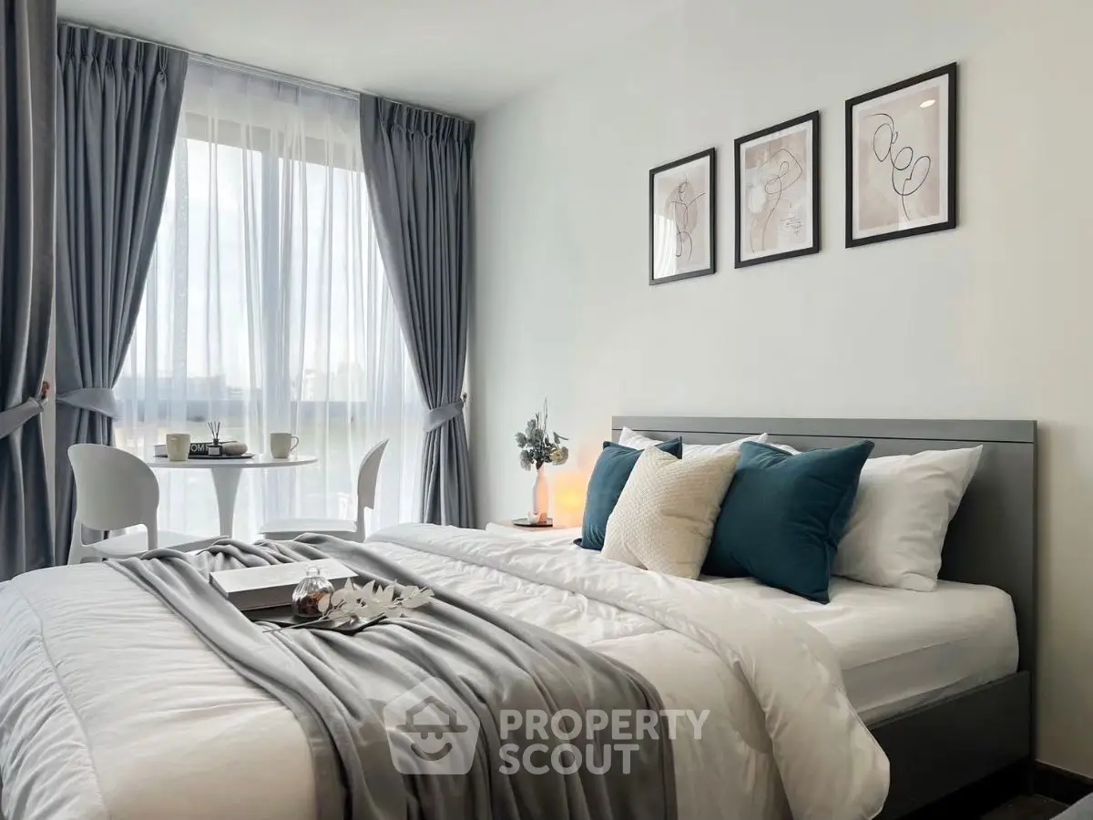 Modern bedroom with elegant decor, large window, and cozy seating area.
