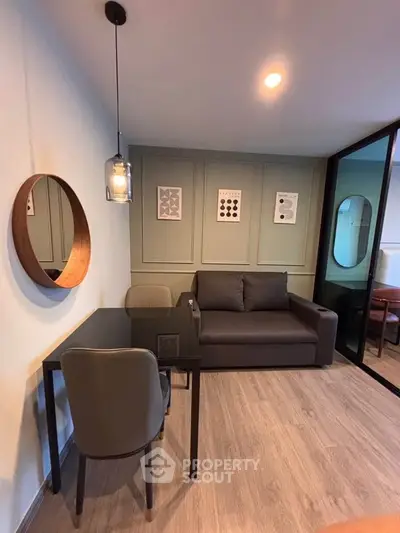 Modern living room with stylish decor, featuring a cozy sofa, sleek glass table, and contemporary wall art.