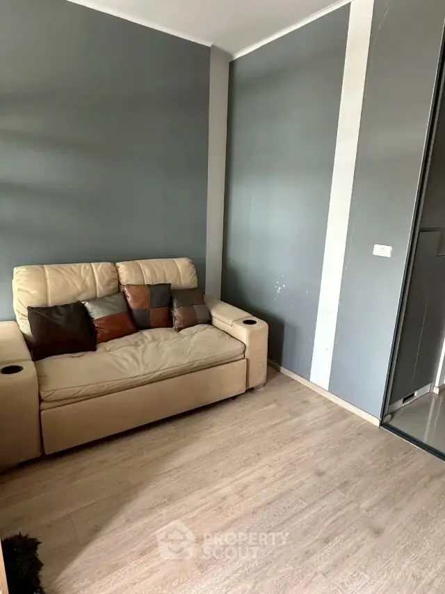 Cozy living room with modern gray walls and comfortable beige sofa, perfect for relaxation.