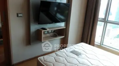 Modern bedroom with wall-mounted TV and large window offering city views.