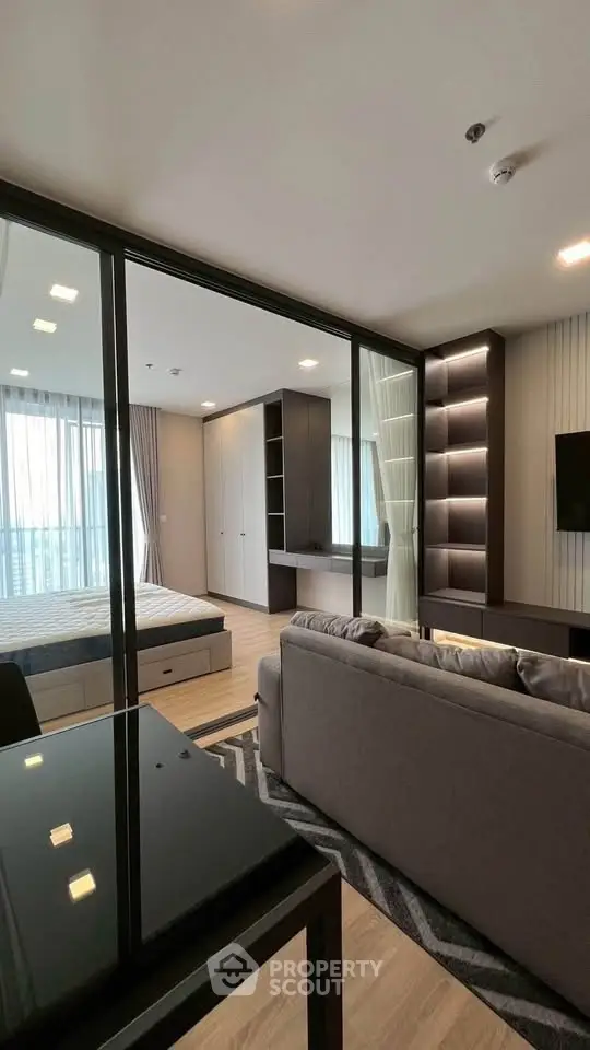 Modern studio apartment with glass partition, stylish living area, and cozy bedroom.