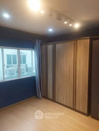 Spacious bedroom with large window and wooden wardrobe