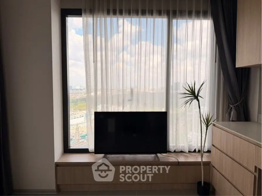 Modern living room with large window and TV, offering a stunning city view.