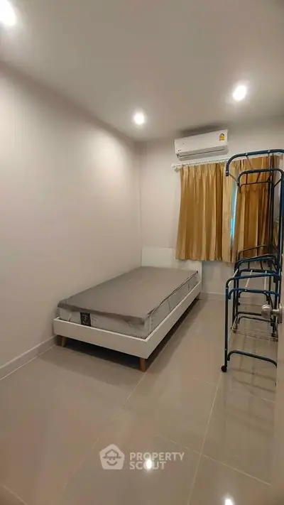 Cozy minimalist bedroom with single bed and air conditioning, perfect for a peaceful retreat.